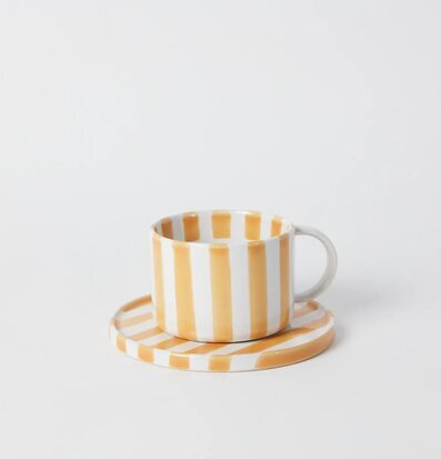 Bild av stilren kopp med fat i gul och vit design