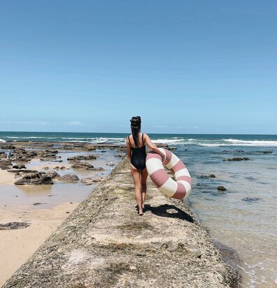 Foto av kvinna vid strandkant med badring i handen