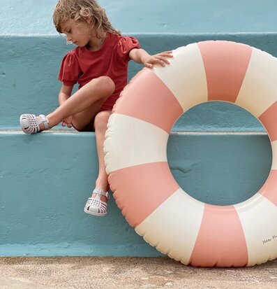 Foto av barn vid poolkant med badring och sandaler