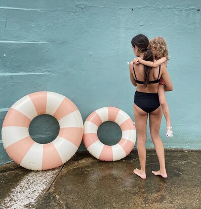 Bild av kvinna och barn vid turkos vägg med badringar