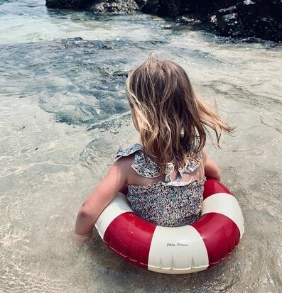 Foto av en flicka vid havet med färgglad badring