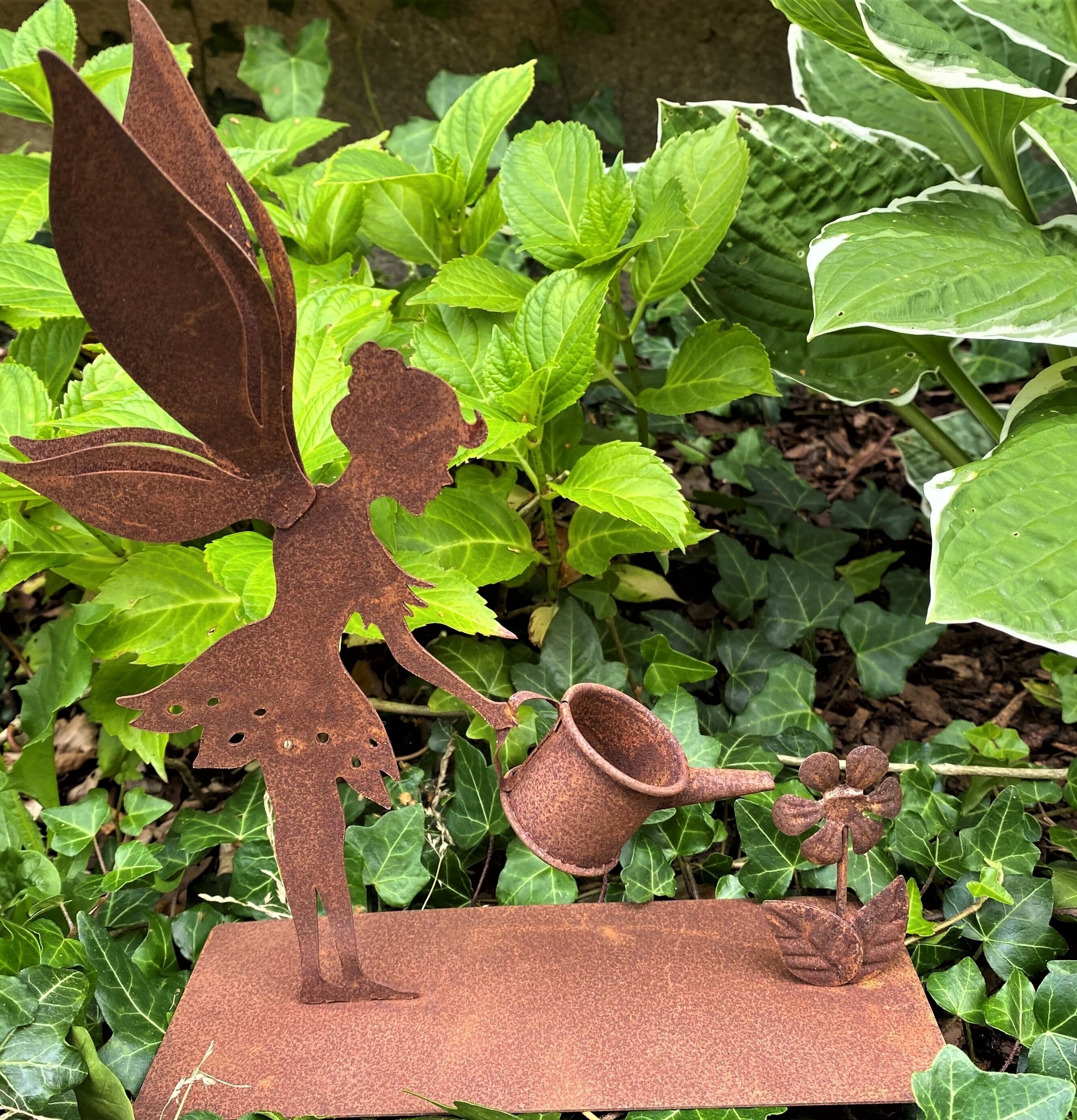 Bild av dekorativ älva med vattenkanna i trädgård