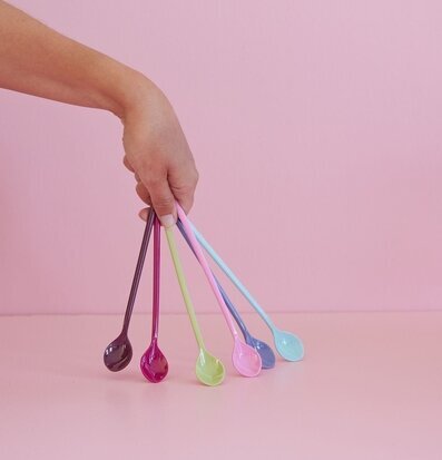 Bild av färgglada långa skedar mot rosa bakgrund