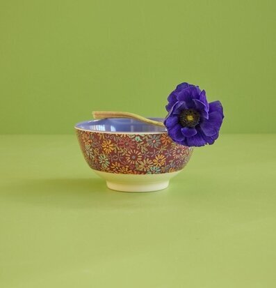 Bild av färgstark skål med blommönster och lila blomma