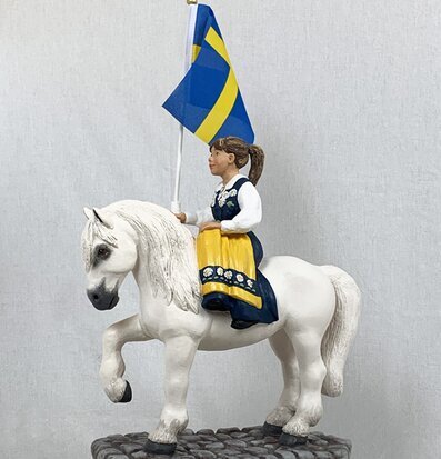 Bild av barn på häst med svensk flagga i folkdräkt