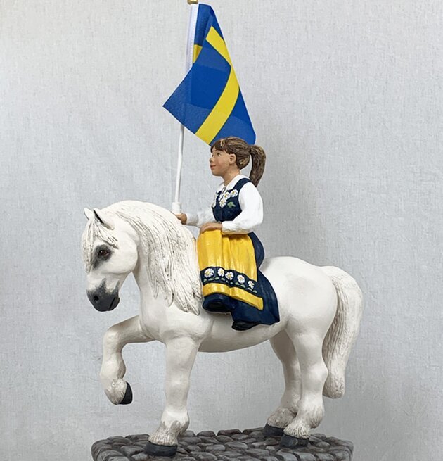 Bild av barn på häst med svensk flagga i folkdräkt