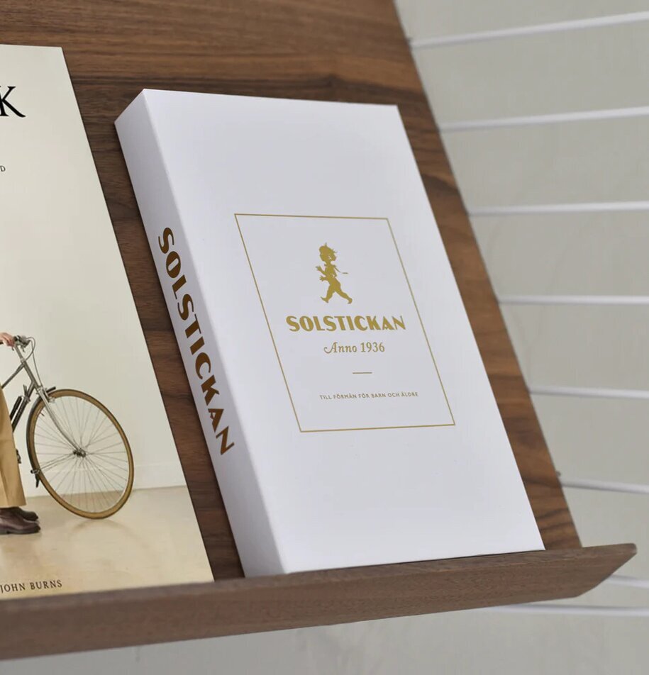 Brandfilt Vit/Guld Tablebook från Solstickan på en trähylla