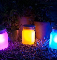 Sun Jar från Suck UK i rosa, gul och blå i en trädgård