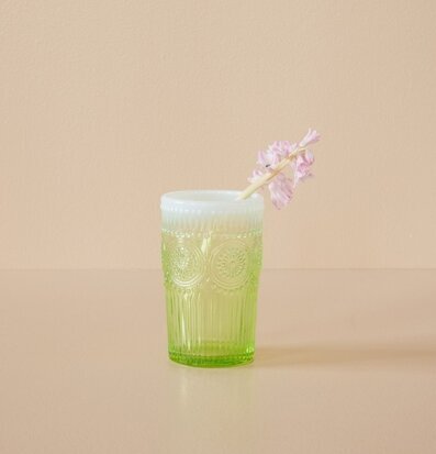 Bild av grönt dricksglas med blomma och eleganta detaljer