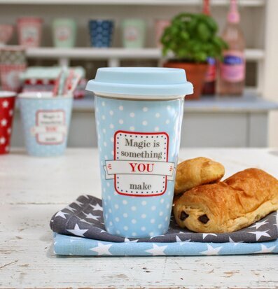 Bild av färgstark termosmugg och croissant på bord