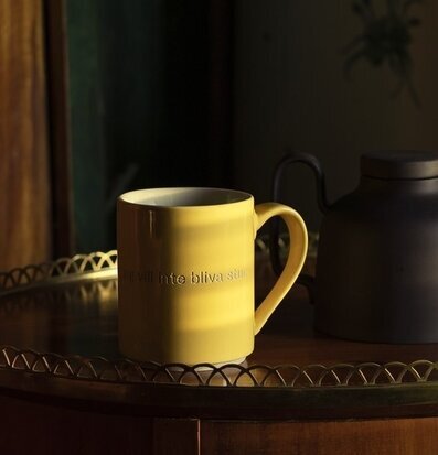 Bild av gul mugg med nostalgisk text och hemtrevlig känsla