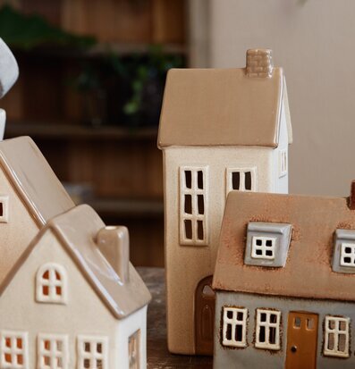 Bild av charmiga keramikhus med ljuslykta i fokus