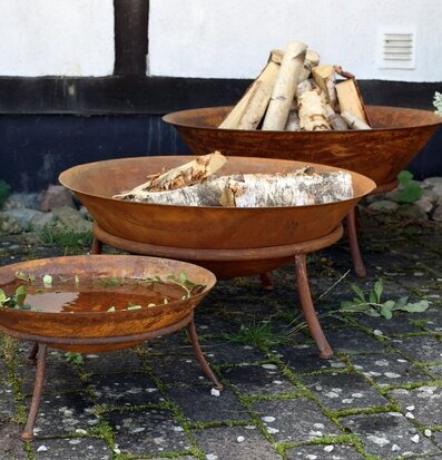 Foto av tre rustika eldfat i harmonisk trädgård