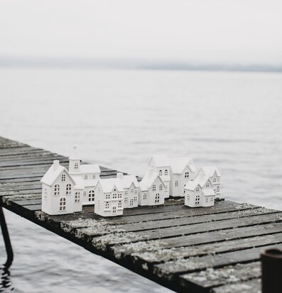 Bild av vita ljusstakar i form av hus vid sjön