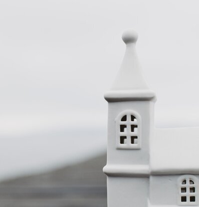 Foto av vit ljusstake i form av ett hus med kyrktorn