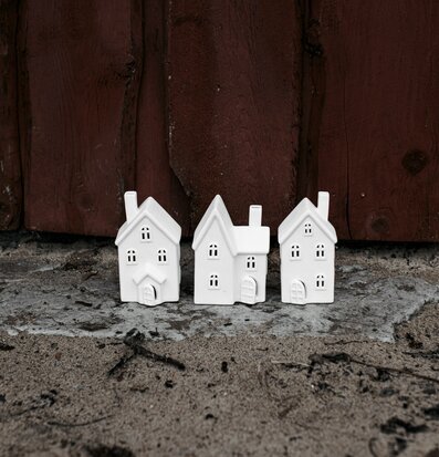 Bild av tre vita husformade ljusstakar på träbakgrund