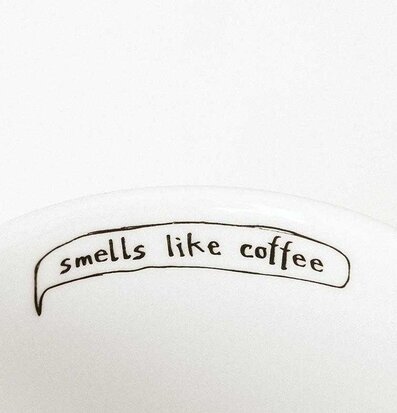 Bild av porslinsmugg med humoristiskt kaffebudskap