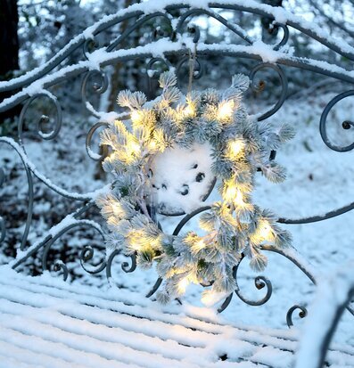 Foto av vinterscen med snötäckt bänk och krans
