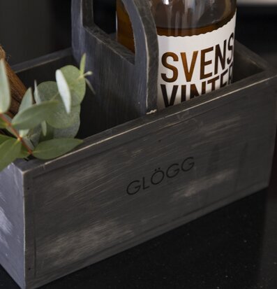 Bild av stilren trälåda med glögg och eukalyptusblad