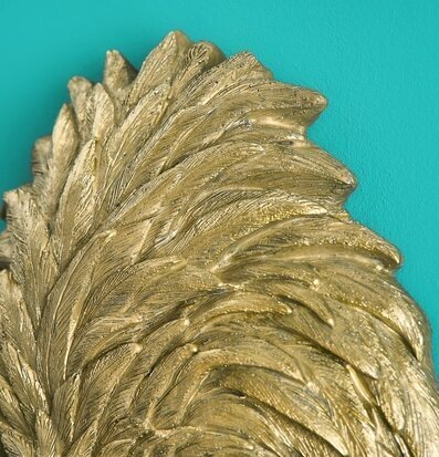 Foto av en gyllene vägglampa med turkos bakgrund