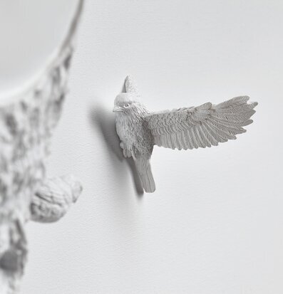 Foto av elegant väggklocka med skulpturerad fågel