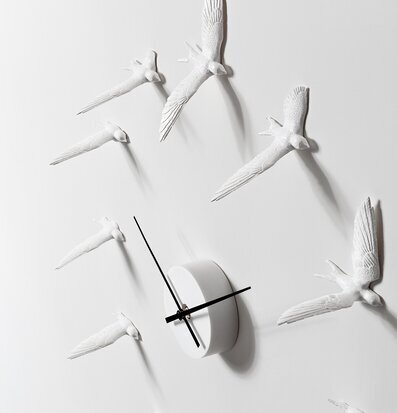 Bild av en elegant väggklocka med svalor i rörelse