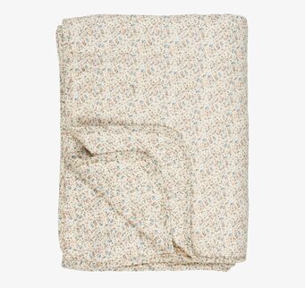 Bild av en quiltad filt med blommönster i krämtoner