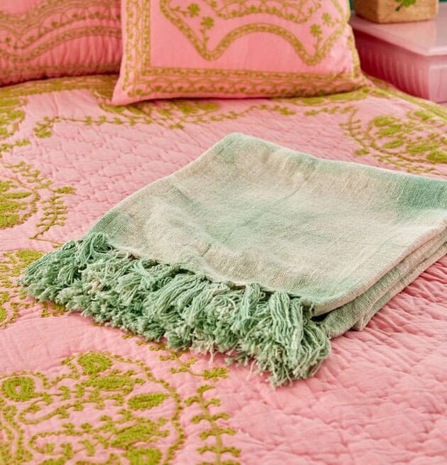 Bomullsfilt Batik Grön från Rice på rosa säng med gröna mönster