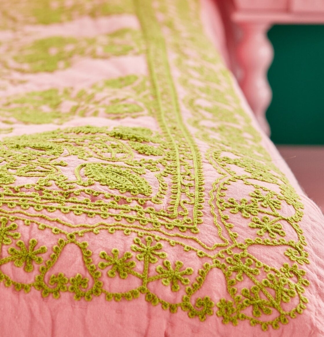 Bild av ett rosa och grönt täcke med eleganta mönster