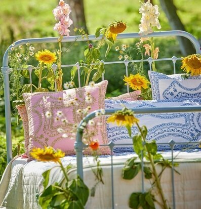 Bild av utomhussäng omgiven av grönska och blommor