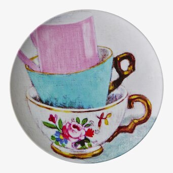 Bild av färgglada tekoppar på dekorativ assiett