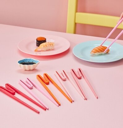 Foto av färgglada ätpinnar och sushi på rosa bord