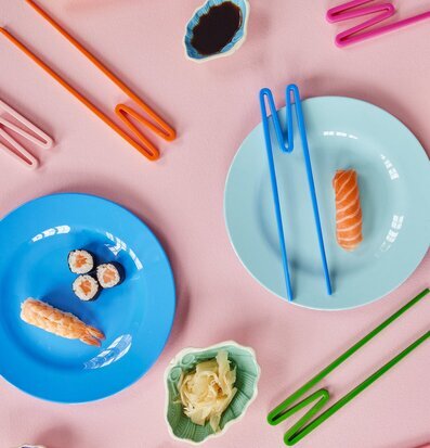 Bild av färgglada ätpinnar och sushi på pastelltoner