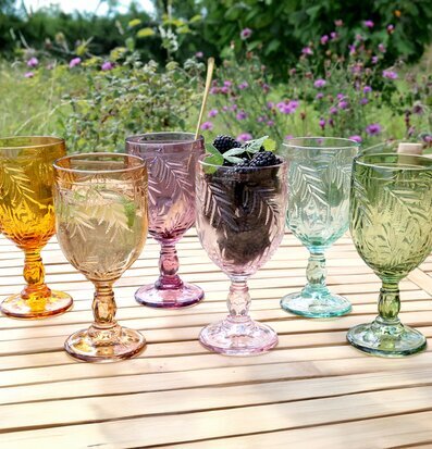 Bild av färgglada vinglas i naturskön trädgårdsmiljö