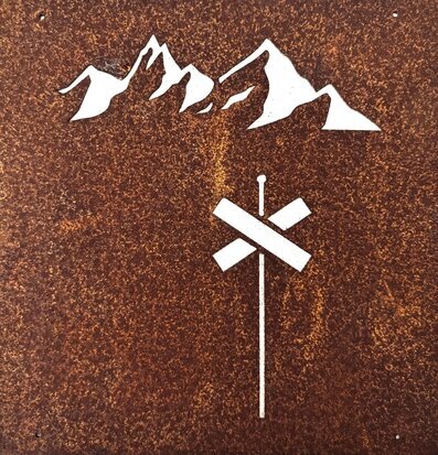 Bild av skylt med berg och ledkryss i rostrött material