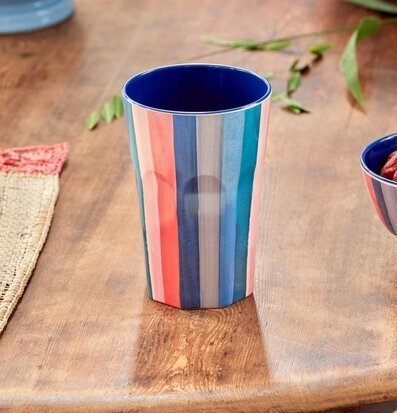 Foto av färgglad mugg på träbord med växt i bakgrunden