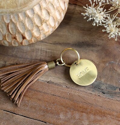 Bild av nyckelring med lädertofs och träbakgrund