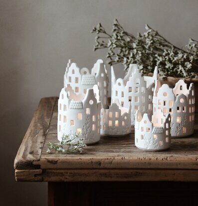 Bild av vackra vita ljushus på rustikt träbord