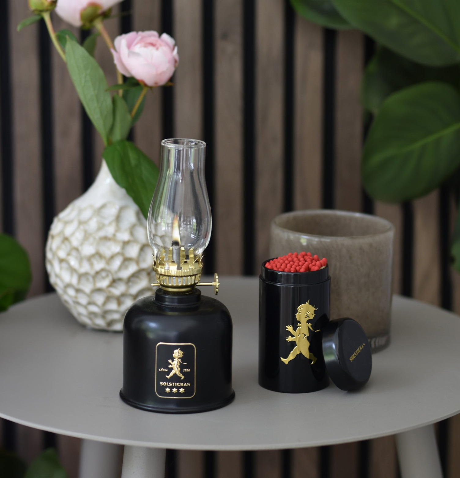 Fotogenlampa Svart/Guld från Solstickan på grått bord