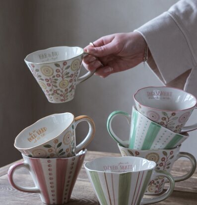 Bild av vackert designade muggar på rustikt träbord