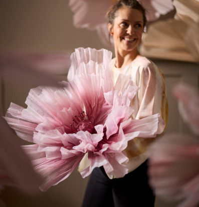 Bild av kvinna med stor konstgjord rosa blomma