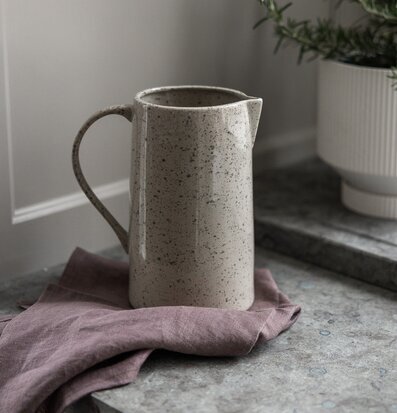 Bild av kanna på stenbänk med linneduk och rosmarin