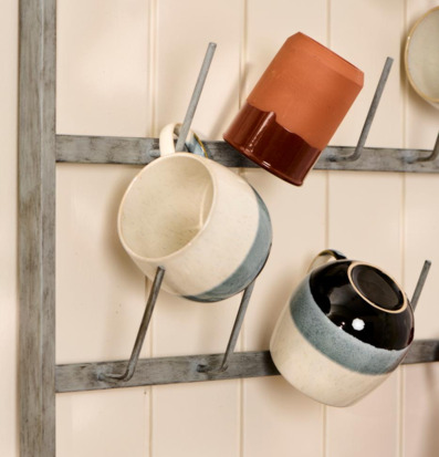 Bild av hyllsystem med färgglada, hängande muggar