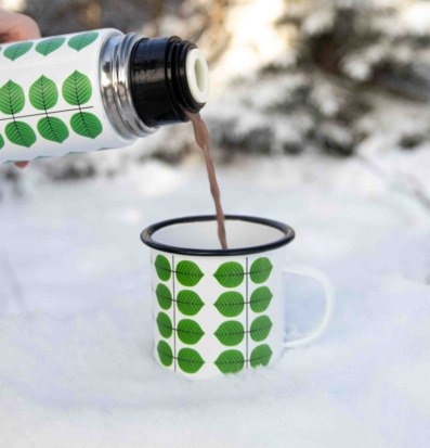 Foto av emaljmugg i vintermiljö med lövmotiv