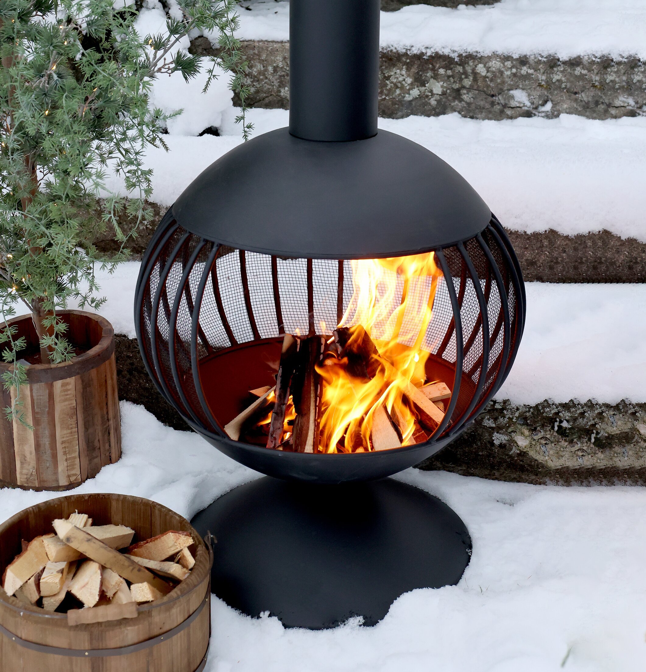 Bild av eldstad i vinterträdgård med snö och växt