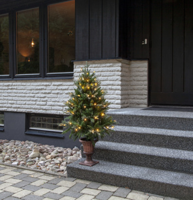 Foto av en inbjudande entré med julgran och belysning