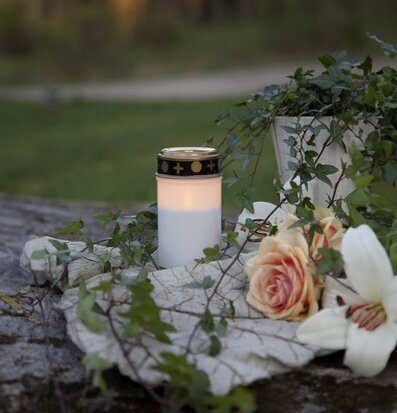 Bild av stillsam utemiljö med gravljus och grönska