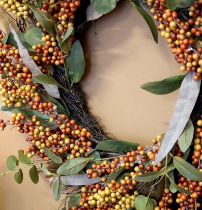 Bild av dekorativ höstkrans med bär och gröna blad
