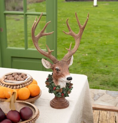 Foto av hjortbyst med krans och naturlig inredning
