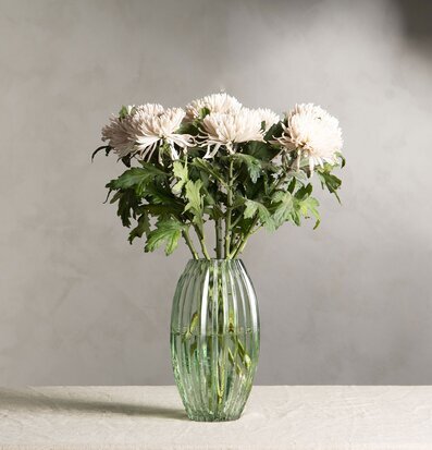 Bild av elegant blomsterarrangemang i grön glasvas